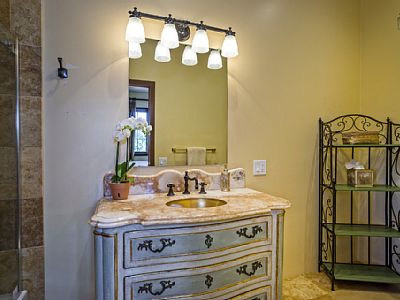 The en suite bathroom for Guest Bedroom 1 features a single sink vanity and a walk in shower.